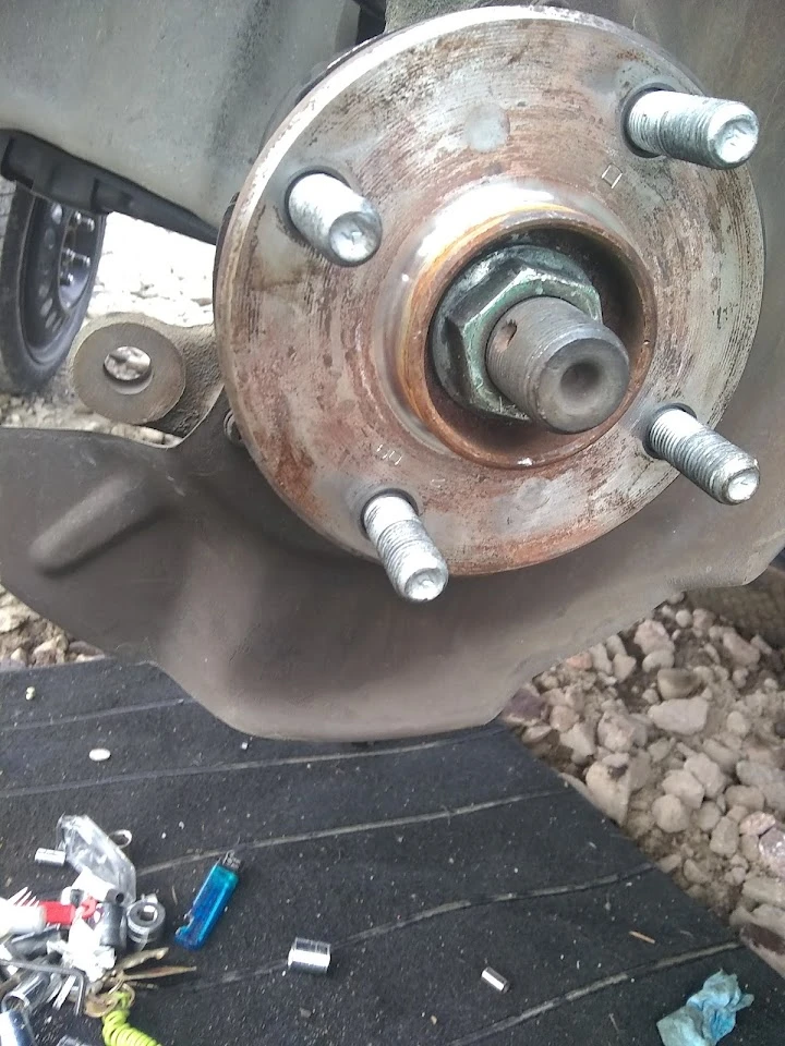 Brake assembly with bolts and rust visible.