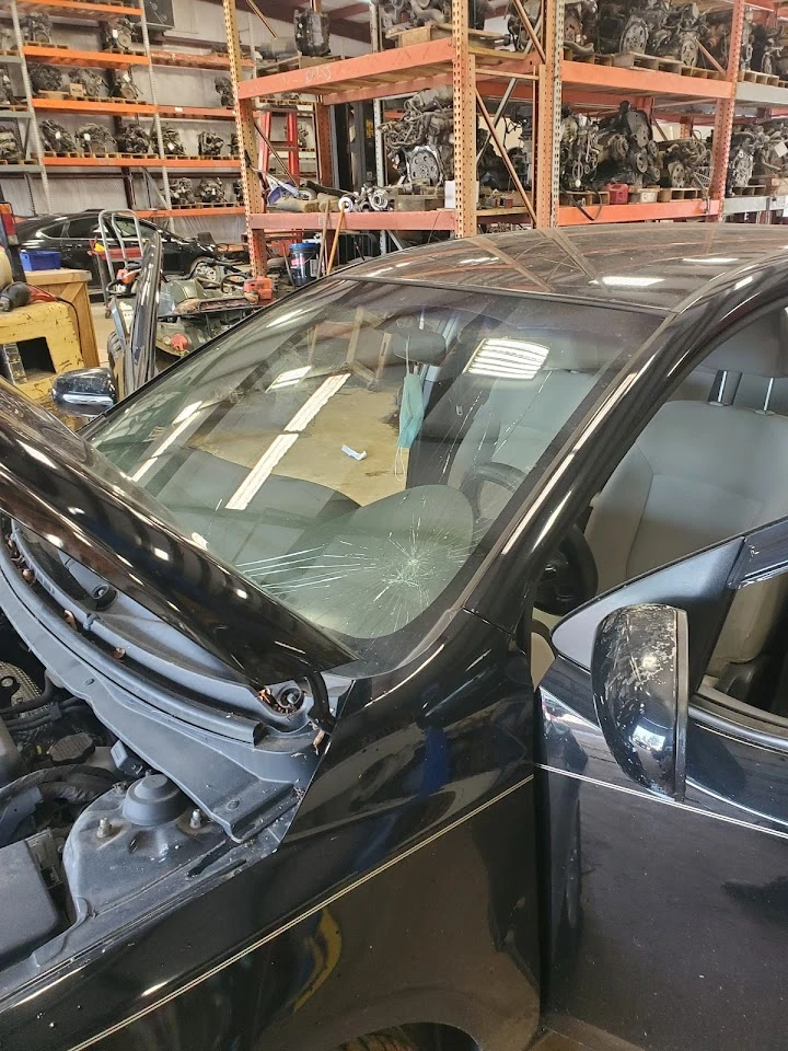 Damaged car with cracked windshield in auto shop.