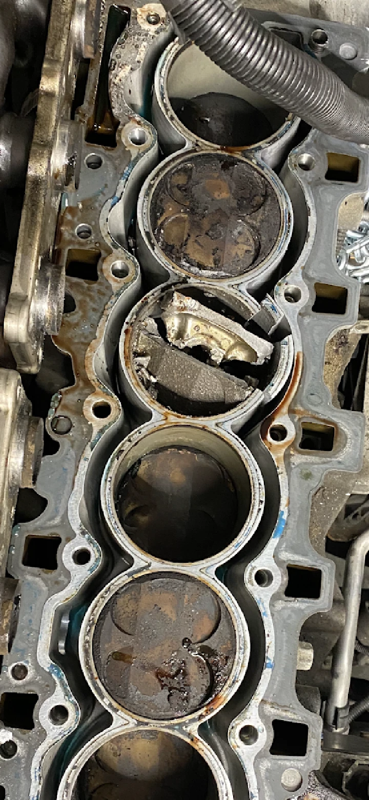 Damaged engine cylinder head with debris inside.