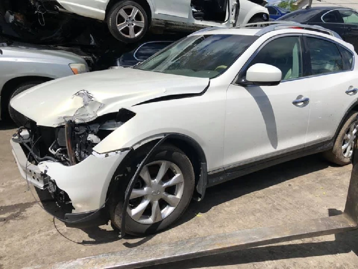 Damaged white SUV at auto wrecking yard.