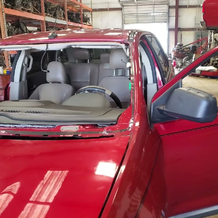 Red car interior with missing windshield in garage.