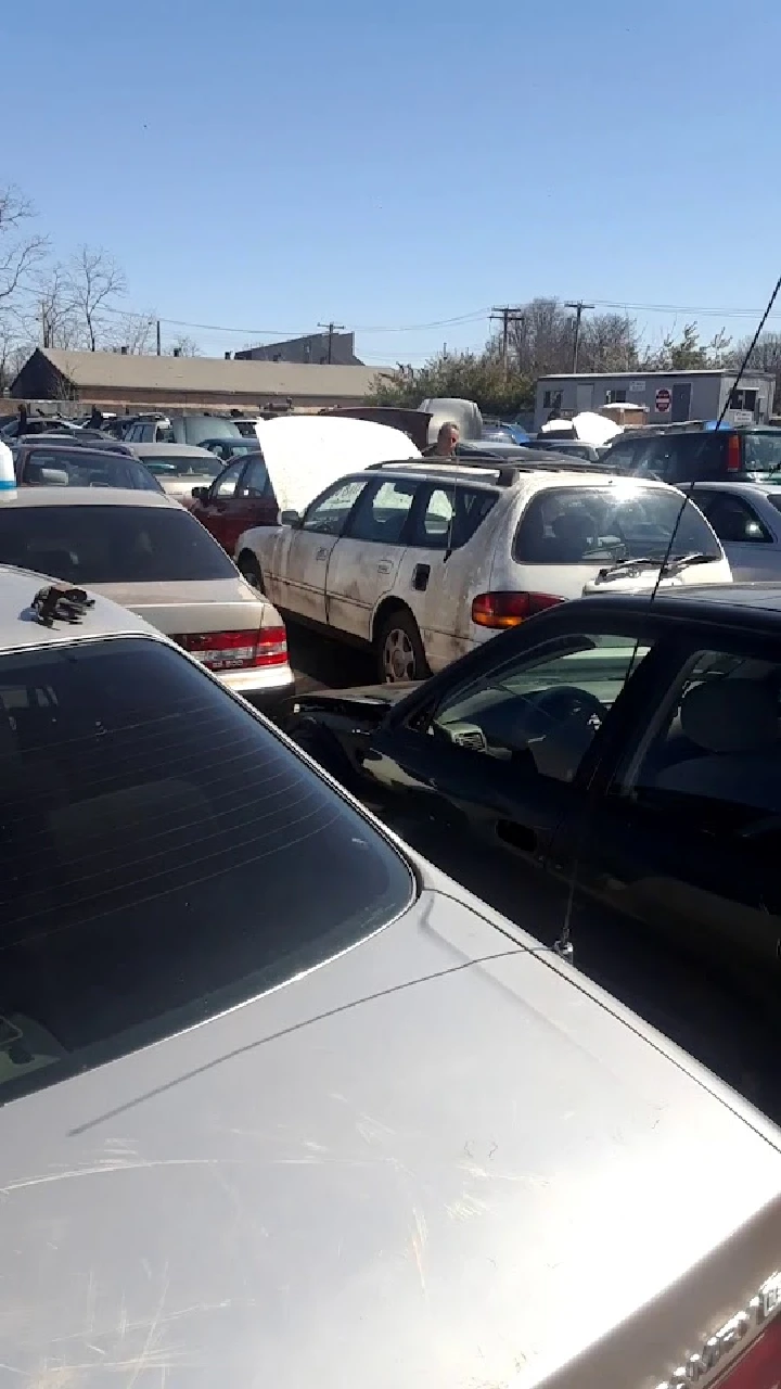 A busy used auto parts yard with parked cars.