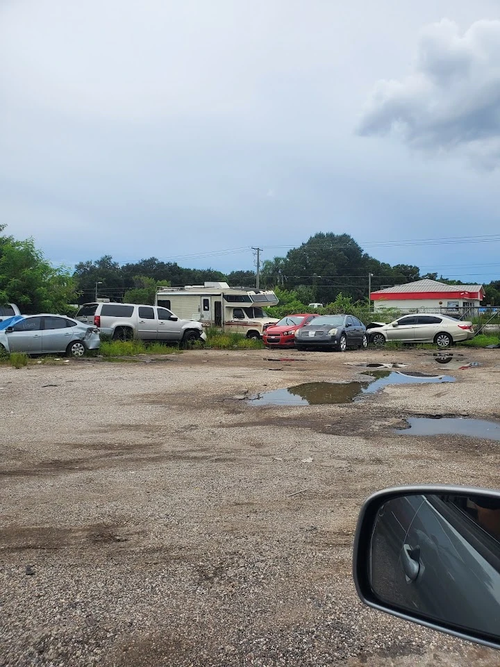 Junk car lot with various vehicles parked.