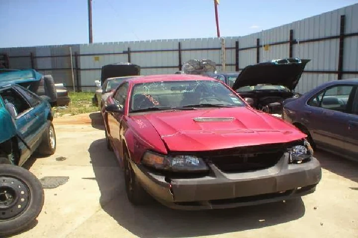 Red salvage vehicle in a junkyard setting.