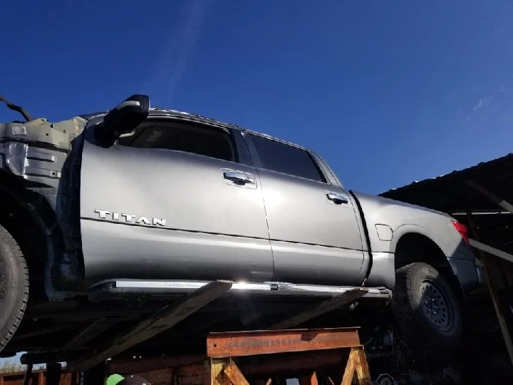 Silver Titan truck parked in auto salvage yard.