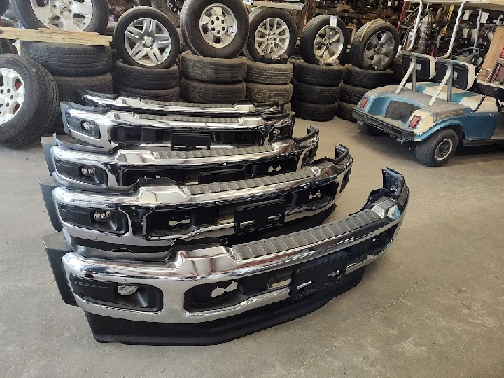 Stack of used auto bumpers in a workshop.