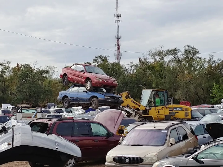 Stacked cars in a junkyard with a bulldozer.