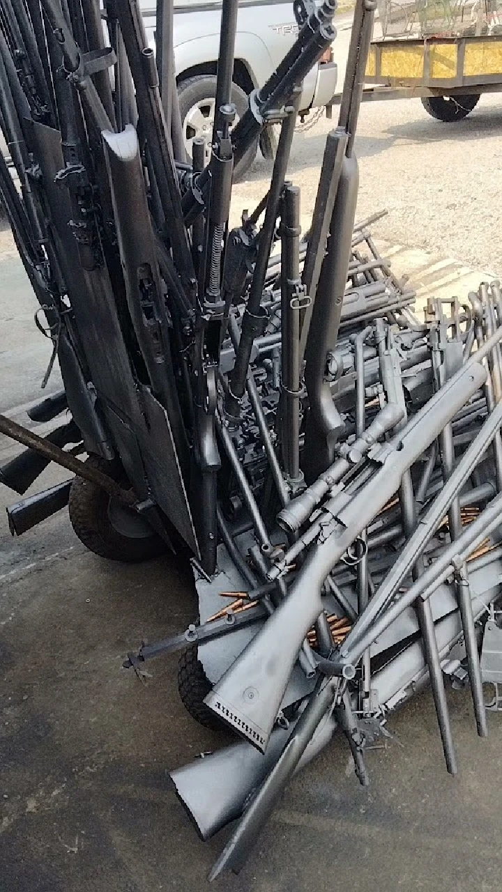 Stacked rifles on a cart ready for recycling.