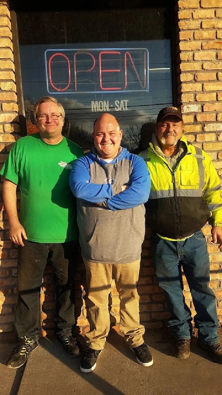 Three workers stand outside Bridgeway Auto Parts.