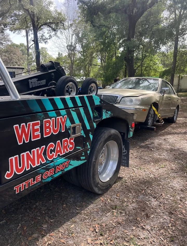 Tow truck with We Buy Junk Cars sign visible.