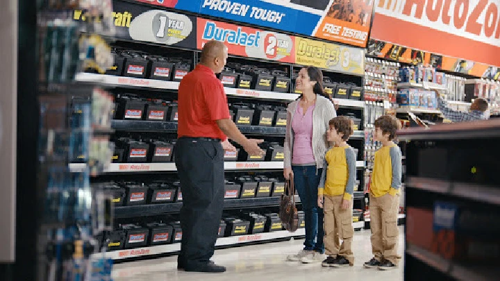 A family consulting an AutoZone employee about batteries.