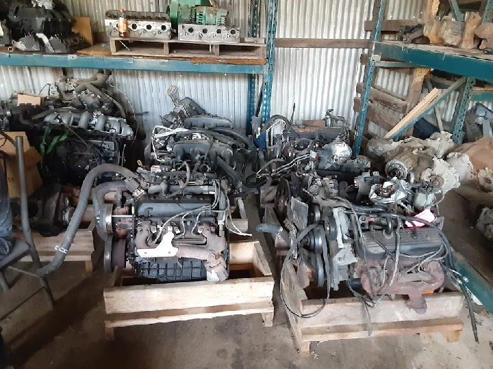 Auto parts and engines stacked in a workshop.