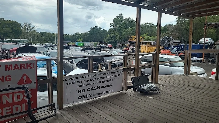 Auto parts yard with cars and signage visible.