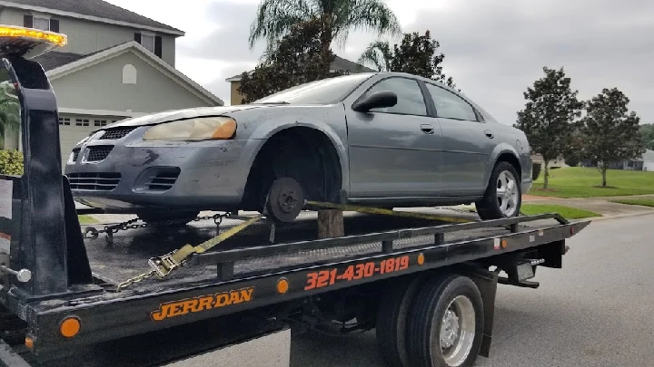 Car being towed on a flatbed truck.