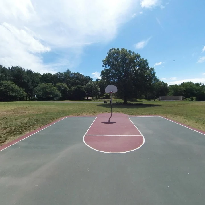 Empty basketball court under a clear blue sky.