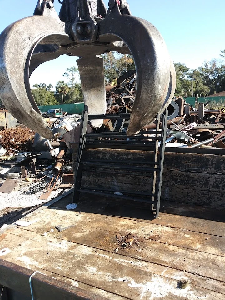 Heavy claw above scrap metal at recycling center.