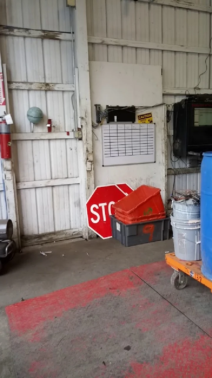 Indoor recycling area with a stop sign and bins.