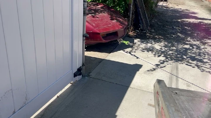 Red car partially visible behind a gate.