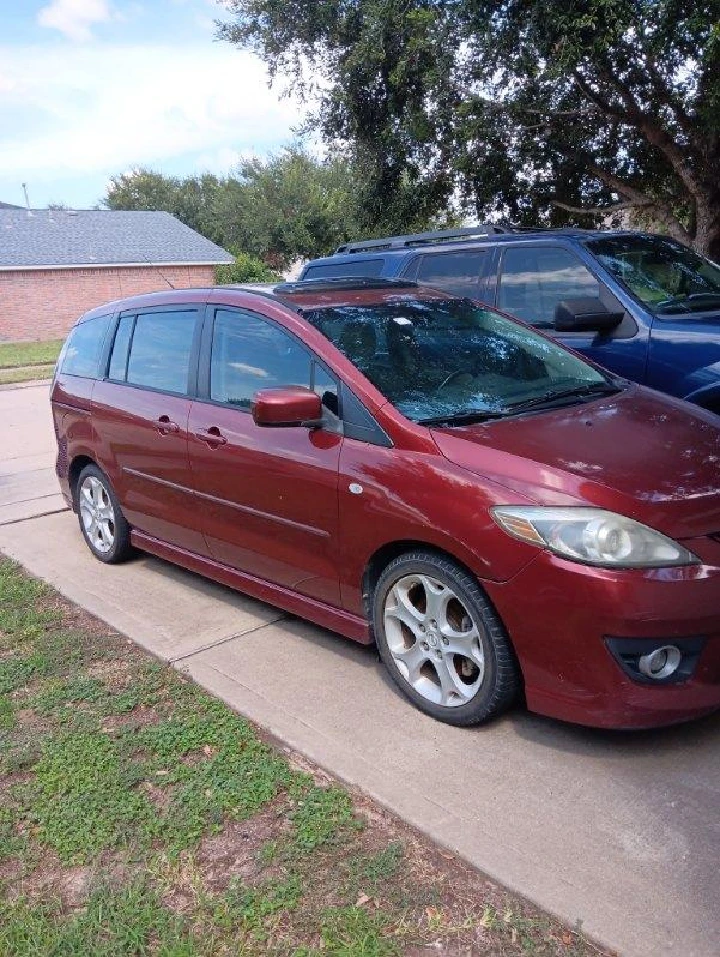 Red minivan parked on a driveway. Grass nearby.