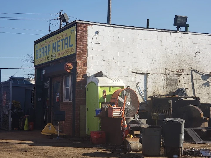 Scrap metal yard with signage and equipment outside.