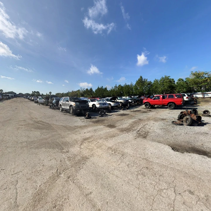 A busy auto salvage yard with parked vehicles.