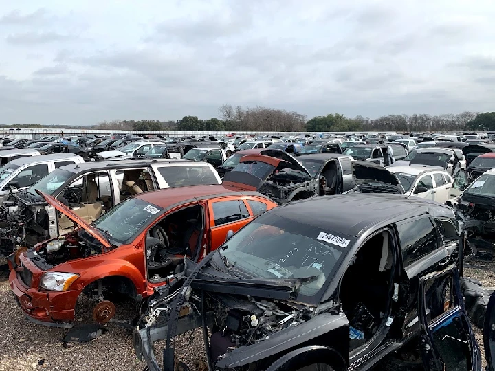 A junkyard filled with various damaged cars.