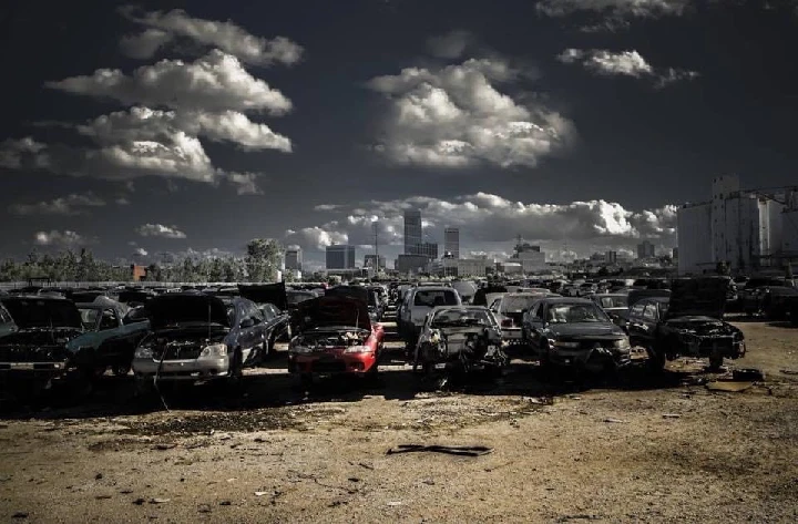 A skyline viewed from a junkyard full of cars.