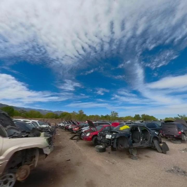 A wide view of a junkyard with parked cars.