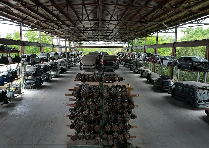 Auto recycling facility with stacked vehicles and parts.