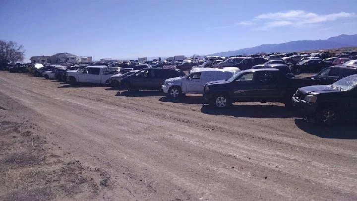 Auto recycling yard with rows of parked vehicles.