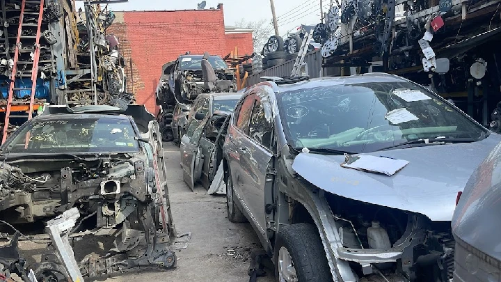 Auto salvage yard with vehicles in various conditions.