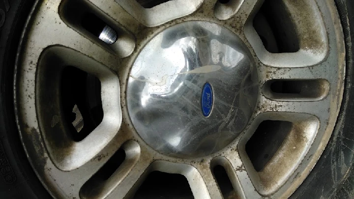 Close-up of a dirty truck wheel hubcap.