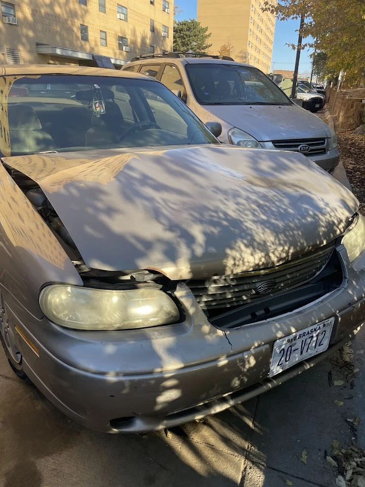 Damaged gray sedan parked in a lot.