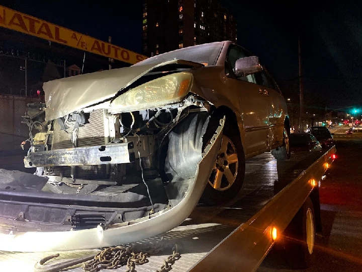 Damaged vehicle on a tow truck at night.