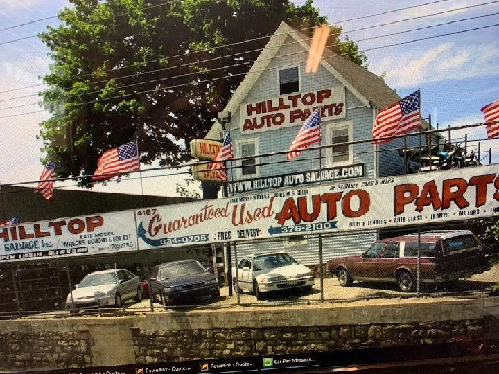 Hilltop Auto Salvage storefront with flags and cars.