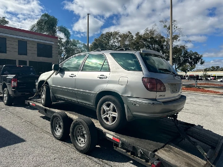 Junk car being towed on a trailer in Orlando, FL.