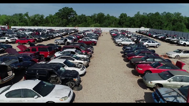 Large auto salvage yard with numerous cars.