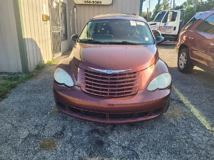 Maroon car parked outside a junk car business.