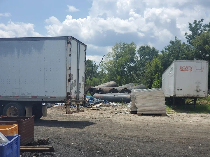 Metal recycling yard with trucks and materials.