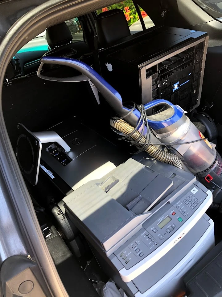 Old electronics and appliances in a car trunk.