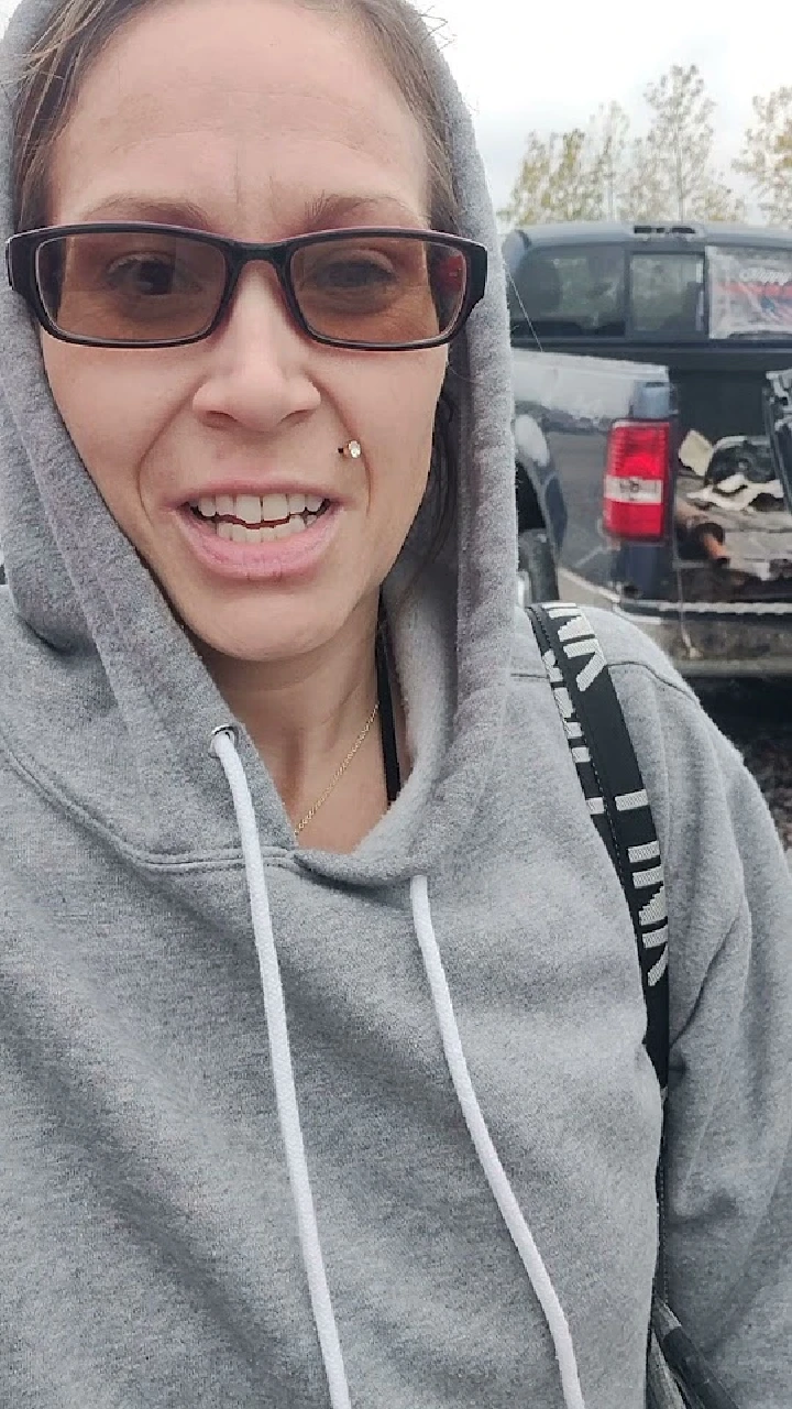 Person in a gray hoodie at a vehicle parts yard.