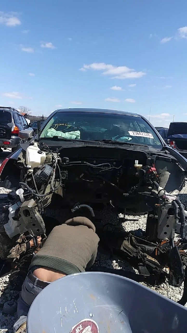 Person working under a car in a junkyard.