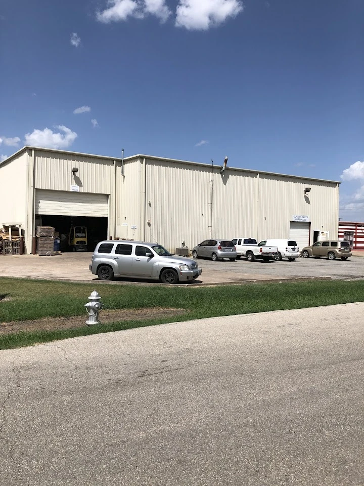 Quality Parts Warehouse exterior with parked vehicles.