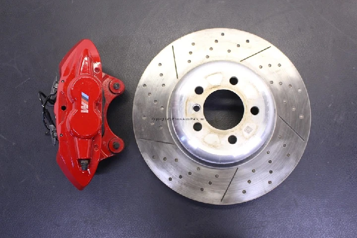 Red brake caliper next to a drilled brake rotor.