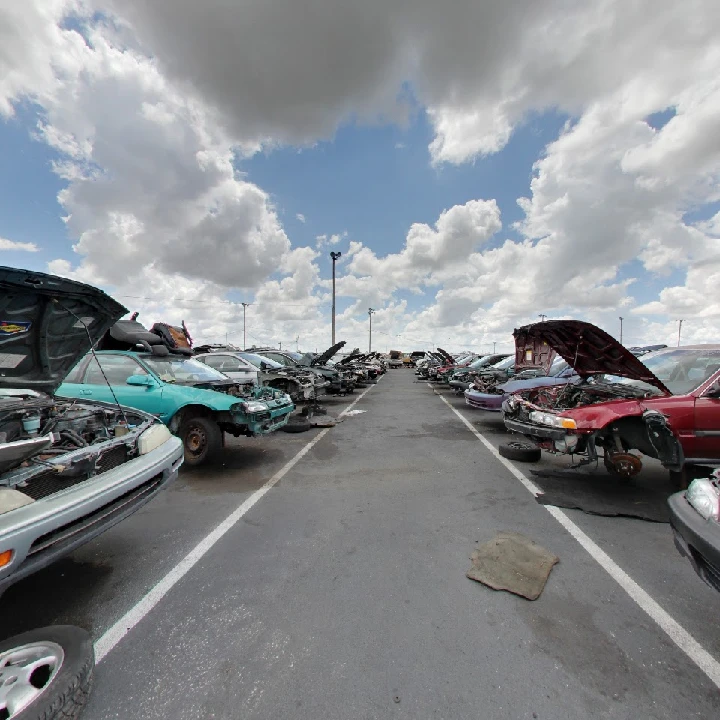 Row of dismantled cars under a cloudy sky.