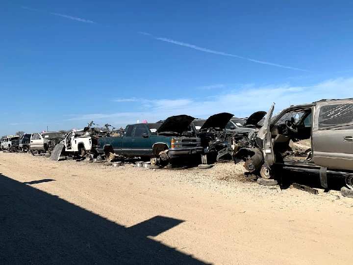 Rows of junked vehicles under a clear blue sky.