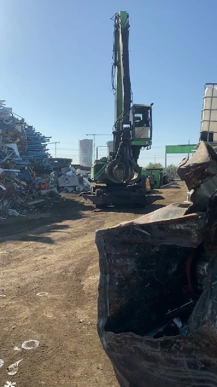 Scrapyard with a recycling crane and metal piles.