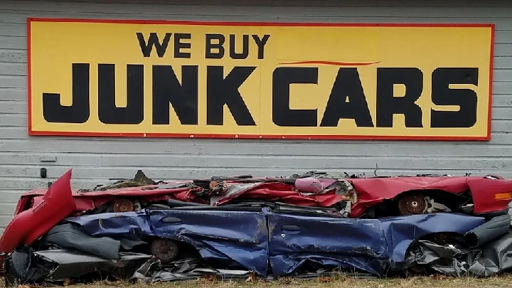 Sign advertising junk car purchases with wrecked cars.