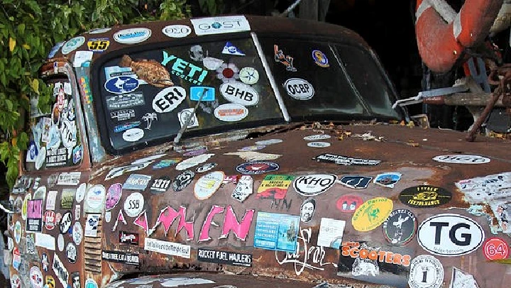 Sticker-covered vintage truck with rust details.