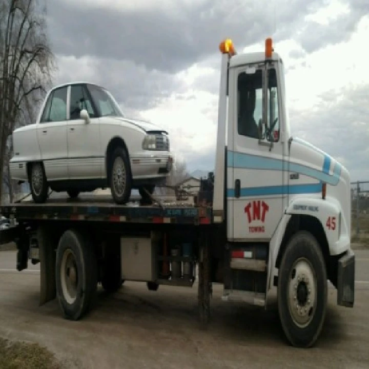 TNT Auto Salvage tow truck with a white car.